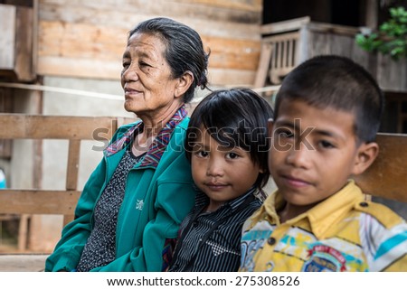Loko, Sulawesi, Indonesia - August 17, 2014: Selective focus on a wrinkled senior woman with pair of children out of focus in the village of Loko, Mamasa region, South Sulawesi, Indonesia.