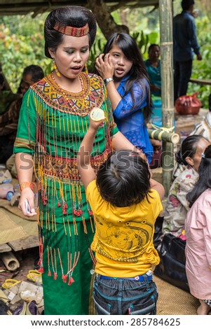 Sangalla, Indonesia - September 8, 2014: Child playing with woman inside a group of people of Toraja ethnicity in traditional attire, in Sangalla, Sulawesi, Indonesia.