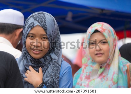 Kuching, Sarawak, Malaysia - August 10, 2014: Portrait of woman wearing traditional Malay hijab and clothings while looking down in a crowded street of Kuching, West sarawak, Borneo, Malaysia.