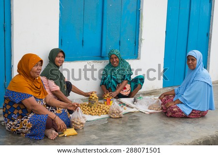 Ampana, Indonesia - August 29, 2014: Unidentified group of women wearing hijab and traditional clothings selling tropical fruit in the street of Ampana, Central Sulawesi, Indonesia.
