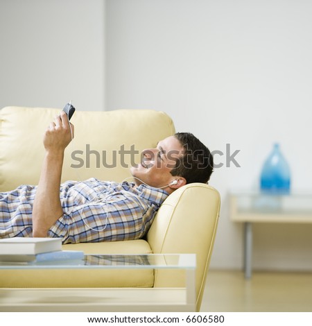 Young man laying on couch listening to headphones