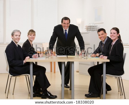 Co-workers sitting at conference table in conference room having meeting lead by supervisor