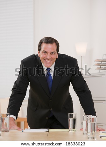 Confident businessman leaning on conference table