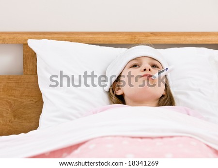 Sick young girl with fever having her temperature taken with thermometer while laying in bed