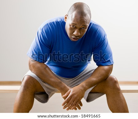 Fatigued man leaning on knees in health club
