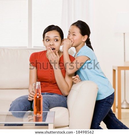 Shocked girl drinking soda listens to friend?s whispered secret