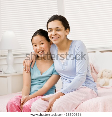 Happy girls in pajamas hugging in bedroom