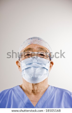 Doctor in sterile scrubs, surgical mask, surgical cap and safety goggles