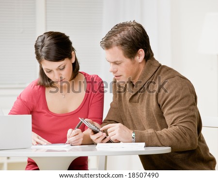 Determined couple using calculator to pay monthly bills