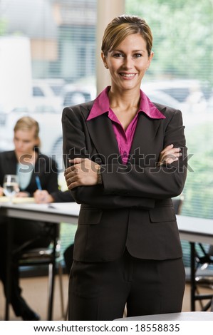 Confident businesswoman standing in front of co-workers in conference room