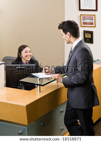 Friendly receptionist greeting man at front desk