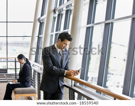 Businesspeople working on laptop and text messaging in office lobby