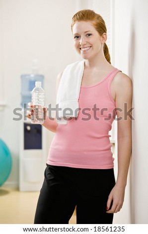Fatigued woman drinking bottle of water after work out