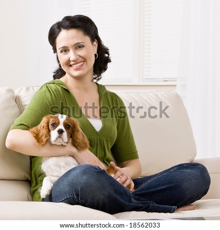 Relaxed woman sitting on sofa holding pet dog