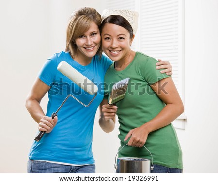 Self-sufficient friends painting with paint roller and paint brush and paint can and renovating home