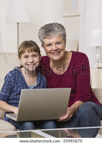 A grandmother and her young granddaughter are working together on a laptop.  Vertically framed shot.