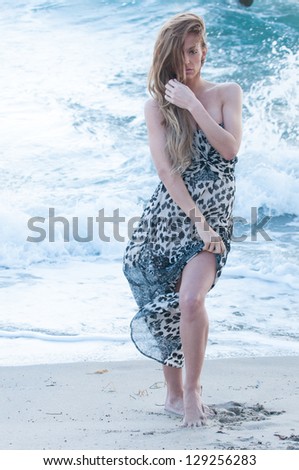 Beautiful woman modeling a print dress at an ocean beach