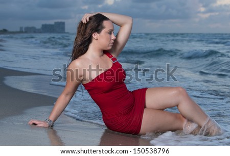 Early morning beach theme with brunette model in  a red dress