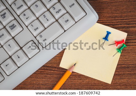 Keyboard, pencil, sticker and drawing pins on the office desk