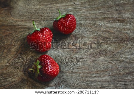Horizontal photo of three strawberry berries on the wooden table