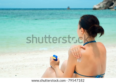Woman applying sun lotion on the beach.
