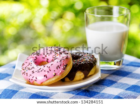 Fresh donuts and glass of milk on nature background.