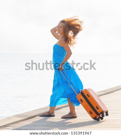 Young woman with suitcase on the pier.