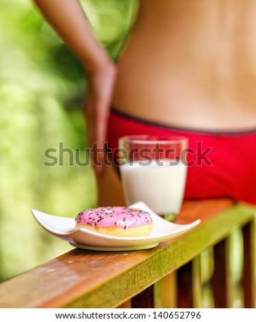 Young woman sitting on terrace with milk and donut.