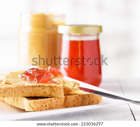 Toasts with peanut butter and strawberry jam on white table. American breakfast.