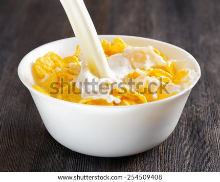 Fresh milk and cornflakes in a white bowl on a wooden table. Organic healthy food rich in minerals and vitamins. Eco food for breakfast.