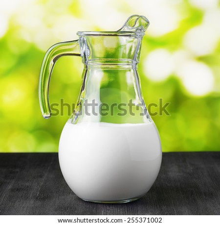 Jug of organic milk on nature background. Half full pitcher. Eco food rich in calcium and vitamins.