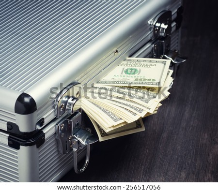 Storage and protection of cash and valuable items. Banking concept. Aluminum briefcase full of money and a stack of hundred-dollar bills. Money and documents in safe hands.