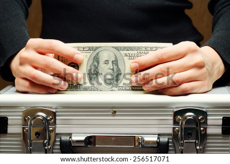 Storage and protection of cash and valuable items. Banking concept. Aluminum briefcase and a hundred-dollar bill. Money and documents in safe hands of bank employee.