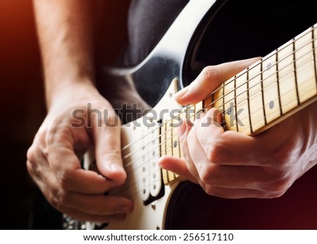 Man playing guitar on a stage. Musical concert. Close-up view. Live rock stars performing musical hits. Guitar solo in the spotlight. Musician pluck the strings with the help of a plectrum.