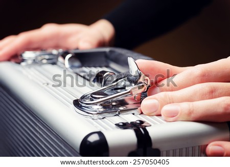 Storage and protection of cash and valuable goods. Business man opens an aluminum briefcase. Money and documents in safe hands of bank employee.
