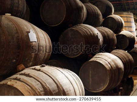 Port wine from the vineyards Douro Valley in Portugal aging in oak barrels stacked in the old traditional dark cellar. Product of organic farming.