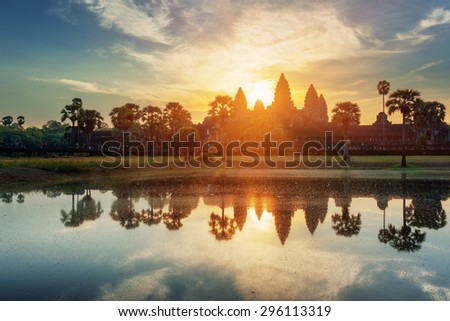 Mysterious towers of ancient temple complex Angkor Wat at sunrise. Siem Reap, Cambodia. Temple Mountain and the sun reflected in lake at dawn. Angkor Wat is a popular tourist attraction.
