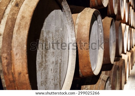 Closeup view of oak barrels stacked in the old cellar with aging Port wine from the vineyards Douro Valley in Portugal. Product of organic farming.