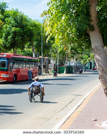 Long Hai, Viet Nam 31 May 2015: Vietnamese man on wheelchair moving on country road, disability man confident and earning living by lottery ticket vendor, is popular business