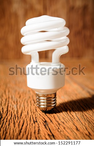white energy saving bulb, Illuminated light bulb, CFL bulb, Realistic photo image on wood background