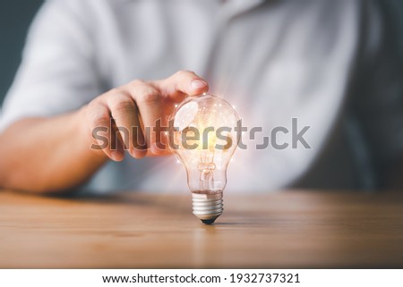 Businessman touching a bright light bulb. Concept of Ideas for presenting new ideas Great inspiration and innovation new beginning.