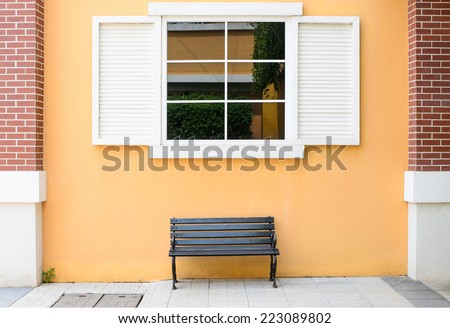 sidewalk scene with wooden bench and orange wall and window