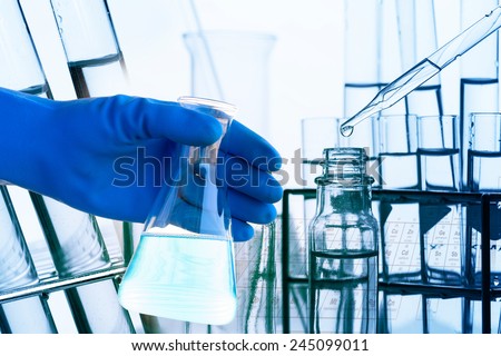 Laboratory glassware with liquid in scientist hand with test tube in rack