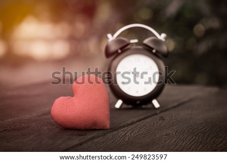 Vintage background with retro alarm clock on table , vintage filter effect
