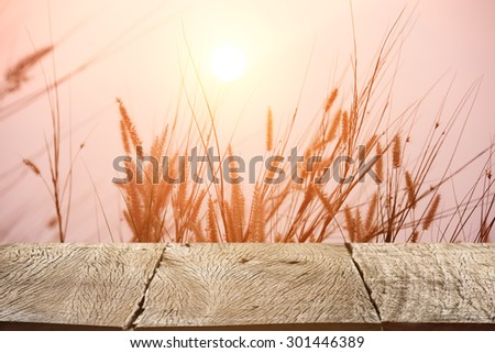 Wood table top on beautiful landscape image with grass flower at sunset background