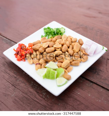 Fried peanuts in white ceramic dish with chilli peppers onions  shallots and lime ,hors d\'oeuvres