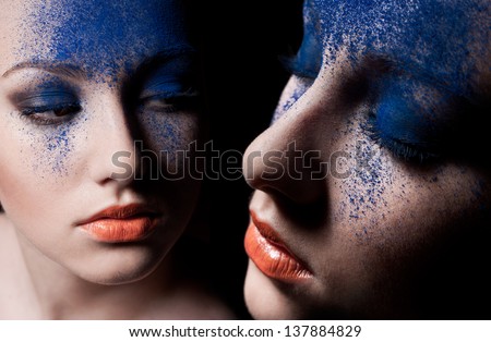 Beauty close-up portrait of beautiful woman model face with magic creative fashion colored make-up. Face painting, cosmetics, beauty and makeup. reflection in the mirror