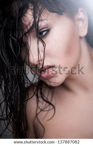 Portrait of a pretty woman with wet hair. Hair falls gently on her your face. Isolated on gray background.