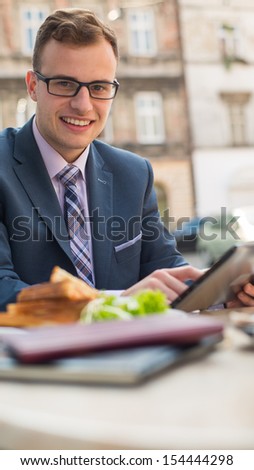 Businessman with surfing the internet of the tablet during breakfast.