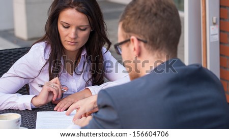 Businessman and businesswomen having a meeting in cafe. She is signing a contract.